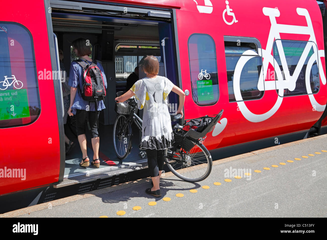 Young woman bringing her bicycle on the electrified railways of Greater Copenhagen. Bicycle compartment. Hellerup station. Copenhagen, Denmark. People. Stock Photo