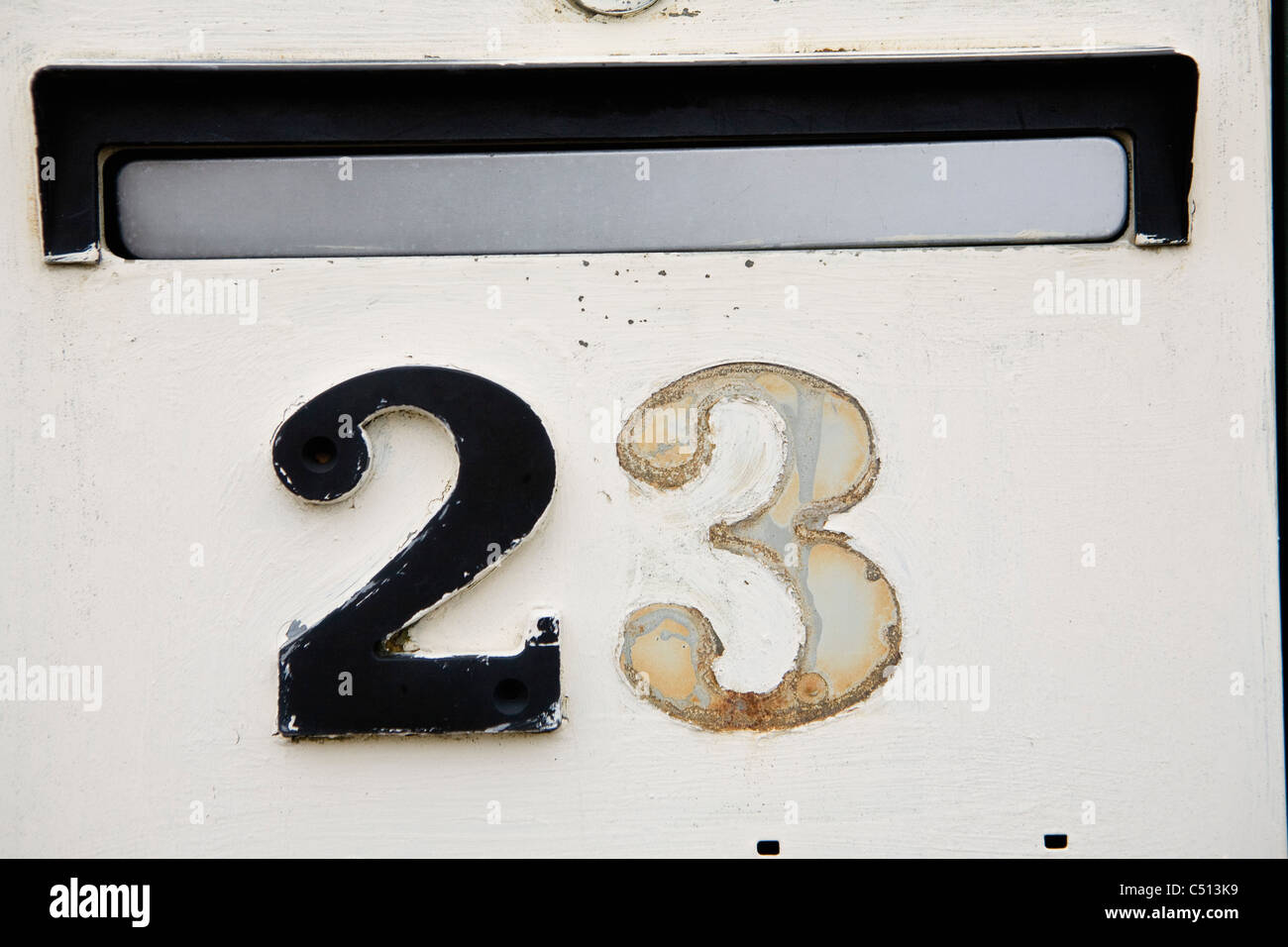 Street address on wall beneath mail slot, one number missing Stock
