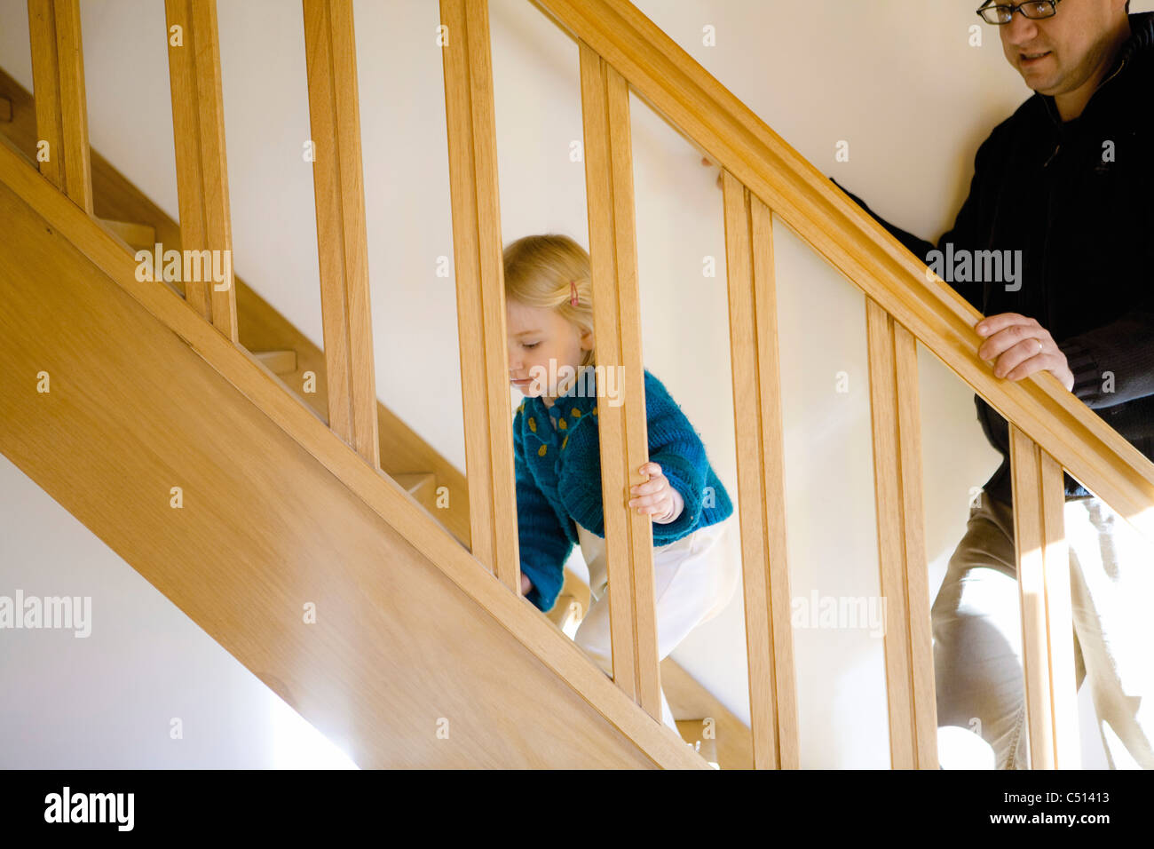 Baby girl climbing stairs while holding onto banister Stock Photo Alamy