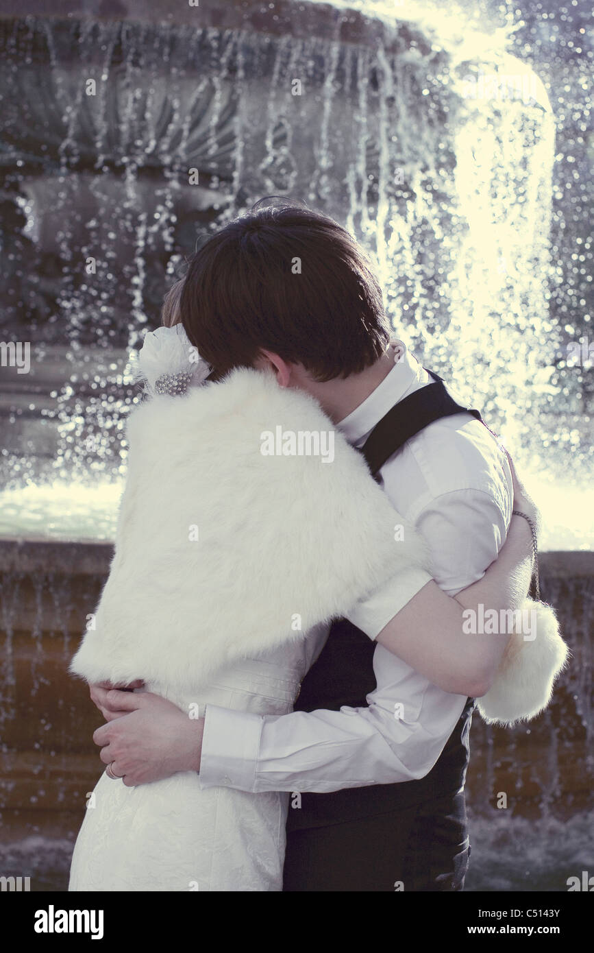 Couple embracing in front of fountain Stock Photo