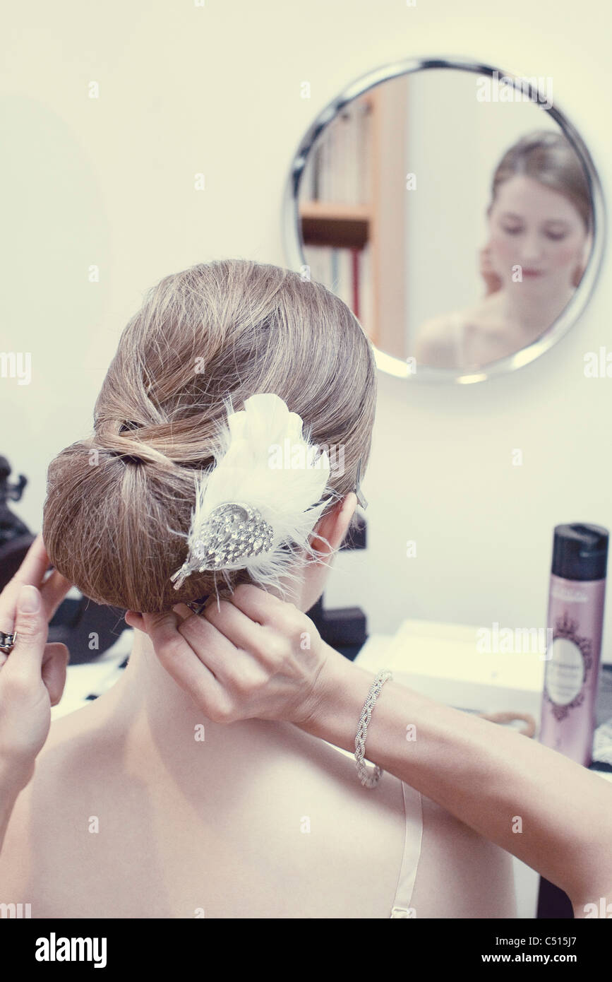 Person preparing woman's hair, woman's reflection in mirror Stock Photo