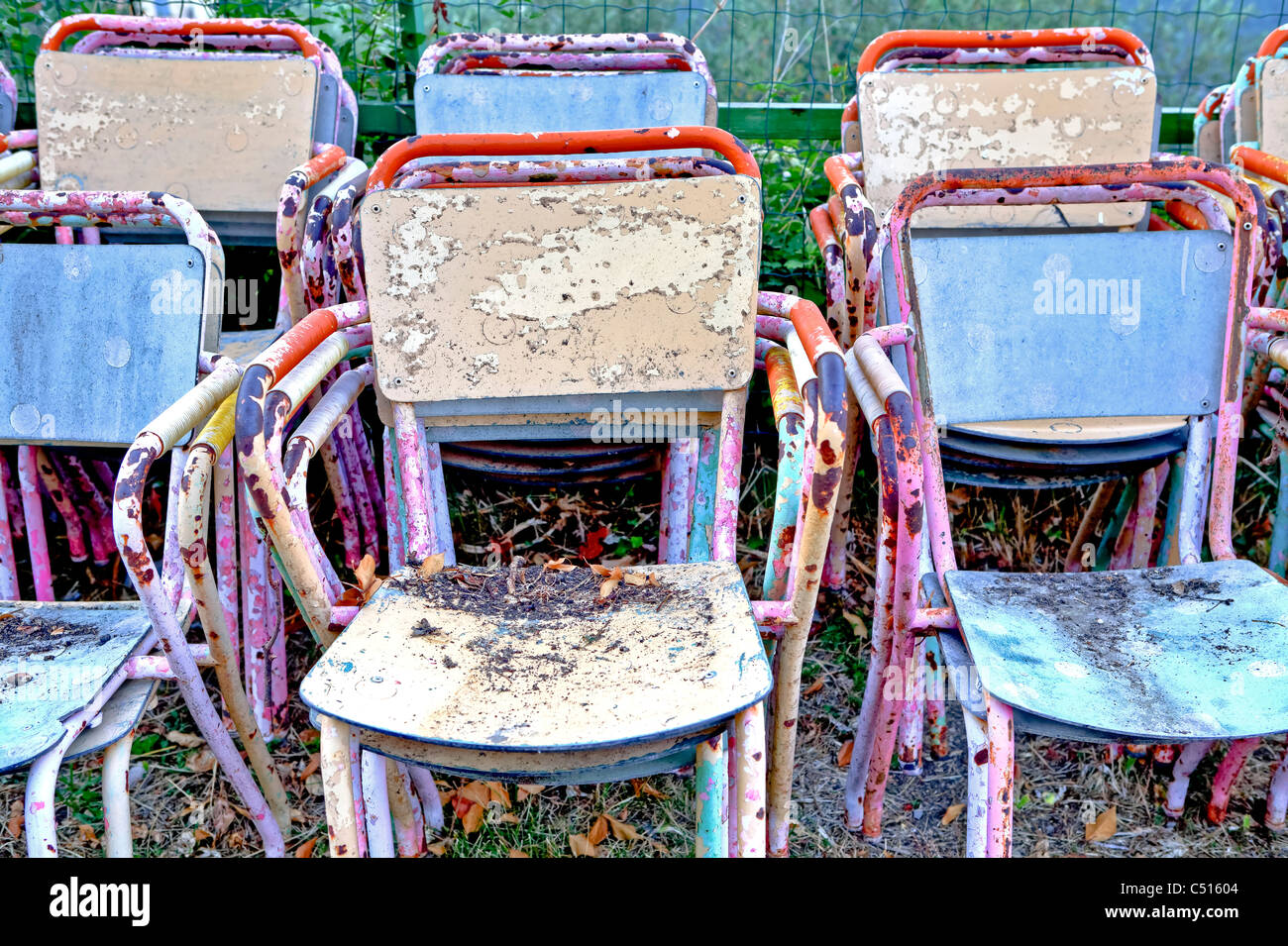 Colourful and rusty old chairs stacked Stock Photo