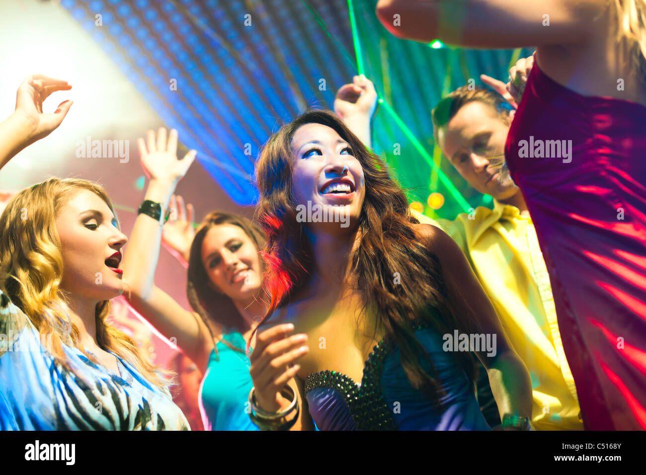 Group of party people - men and women - dancing in a disco club to the ...