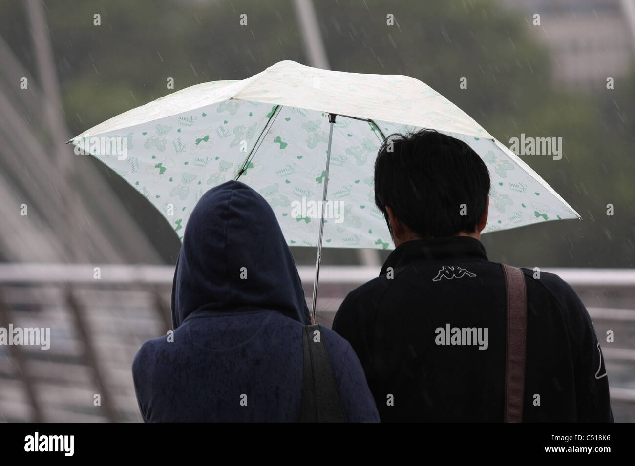 Two people sharing an umbrella in the rain while walking over the