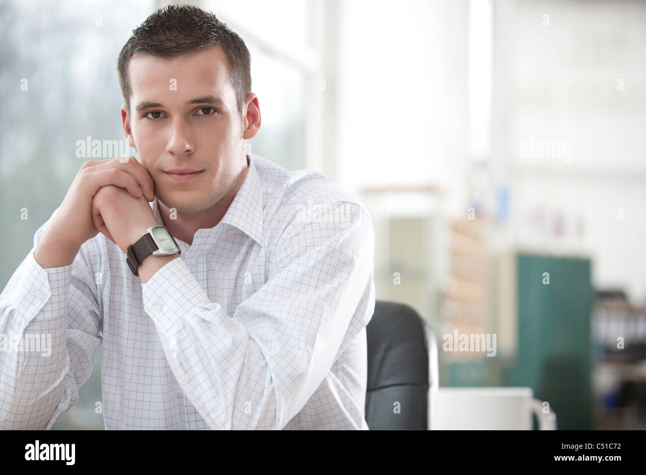 portrait of young businessman sitting at desk Stock Photo - Alamy