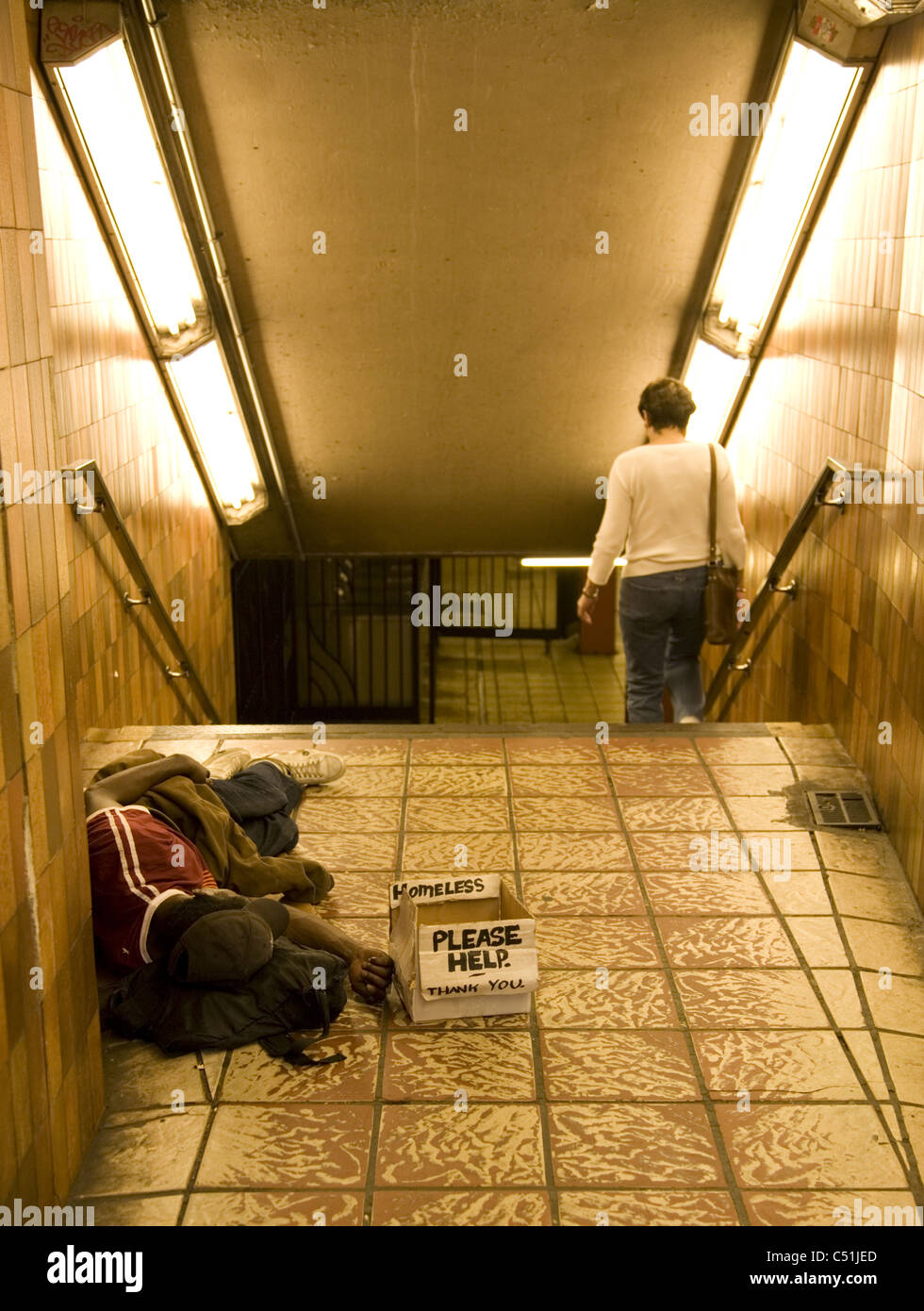 Homeless man sleeping in subway entrance/exit, Rockefeller Center, New York City. Stock Photo