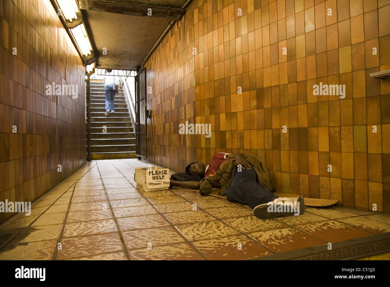 Homeless man sleeping in subway entrance/exit, Rockefeller Center, New York City. Stock Photo