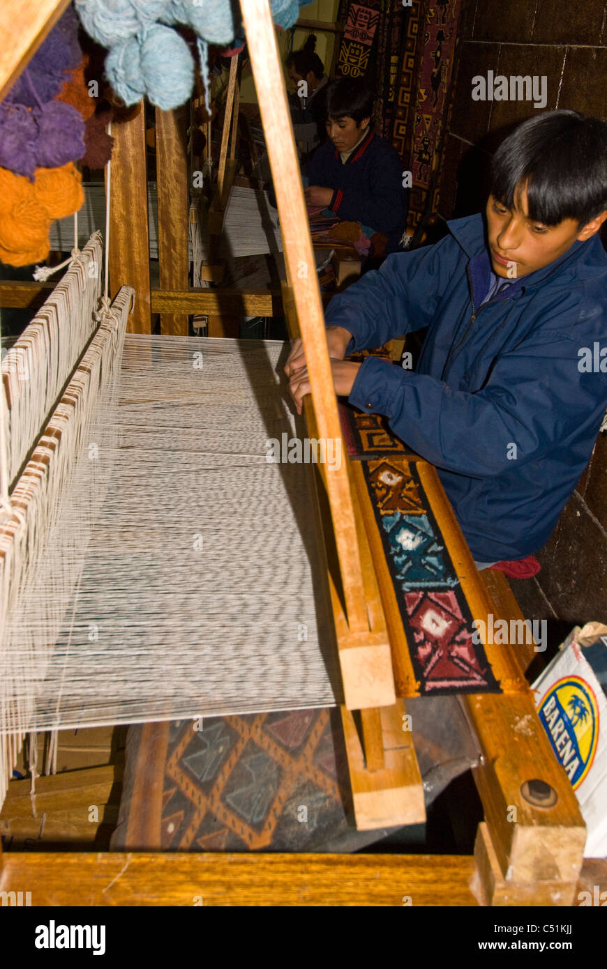 Young Peruvian weaving alpaca wool on loom in factory in Cusco Peru Stock Photo