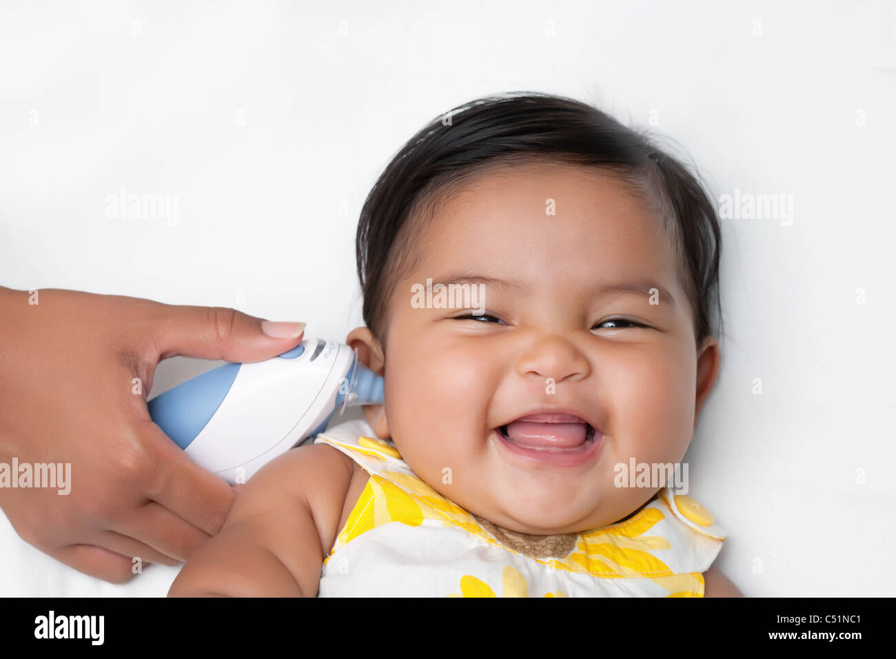 Healthy baby having temperature taken using an infrared ear thermometer Stock Photo