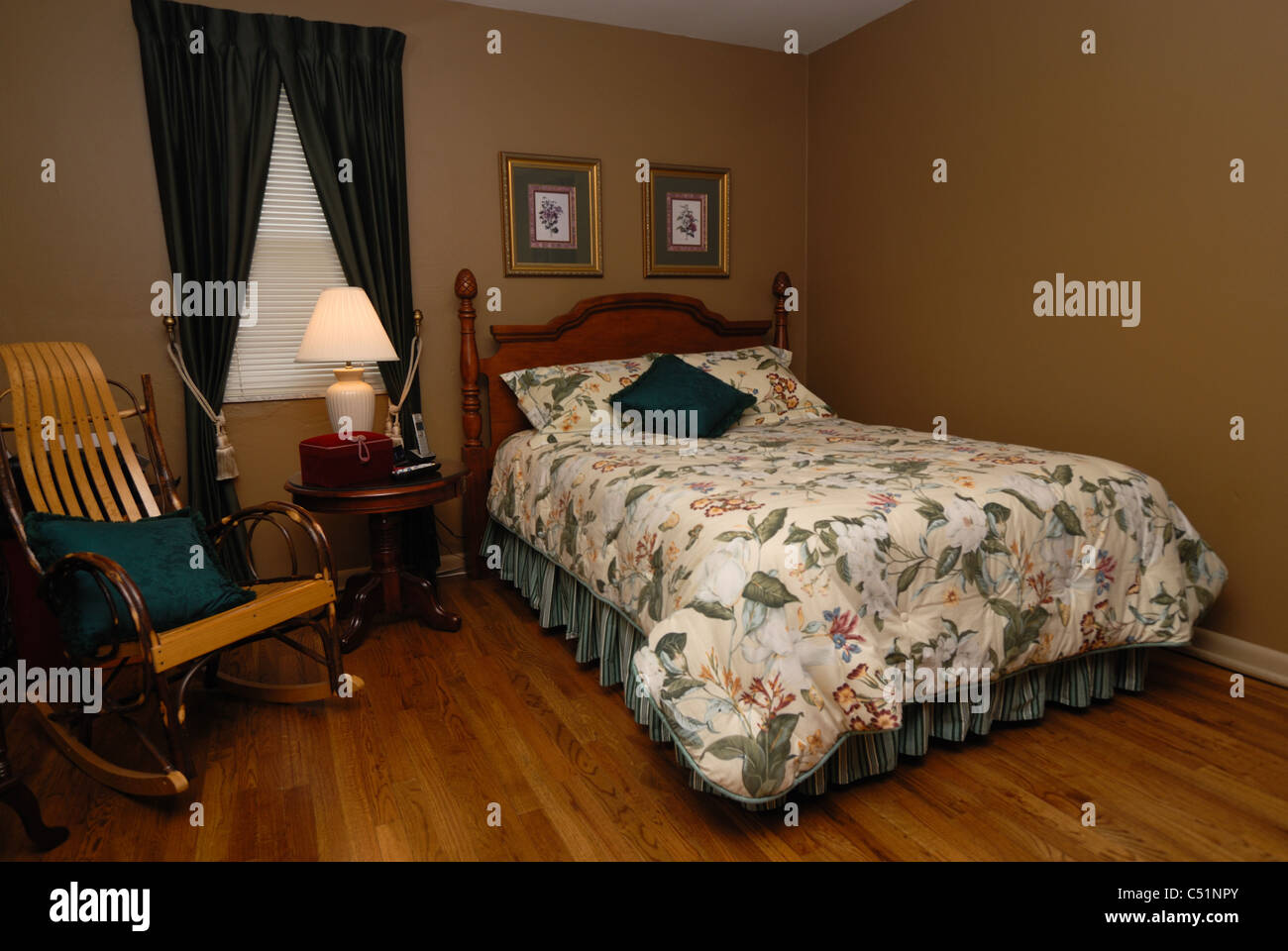 A wide angle shot of the interior of a home, a bedroom decorated in pale yellow and dark green. Stock Photo