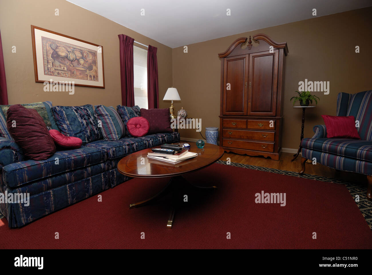 A wide angle shot of the interior of a home, a living room decorated in burgundy and blue. Stock Photo