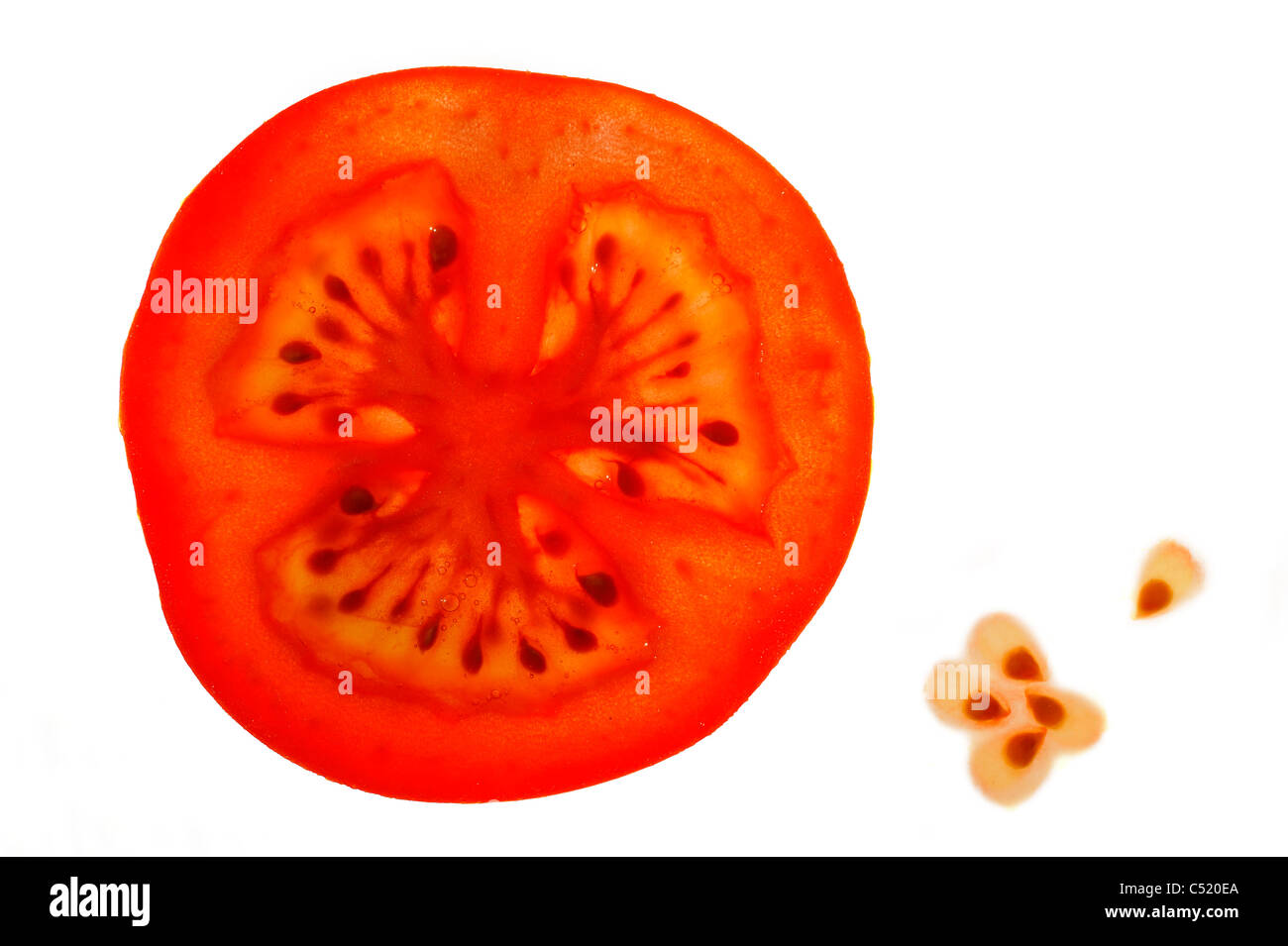 Slice of tomato (Solanum lycopersicum / Lycopersicon esculentum) and seeds on white background Stock Photo