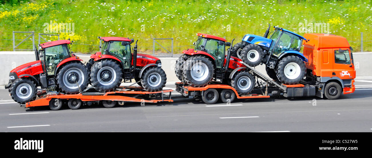 Side view of a load of new agriculture farm tractors on adjustable low loader with trailer behind hgv lorry truck driver travelling along UK motorway Stock Photo