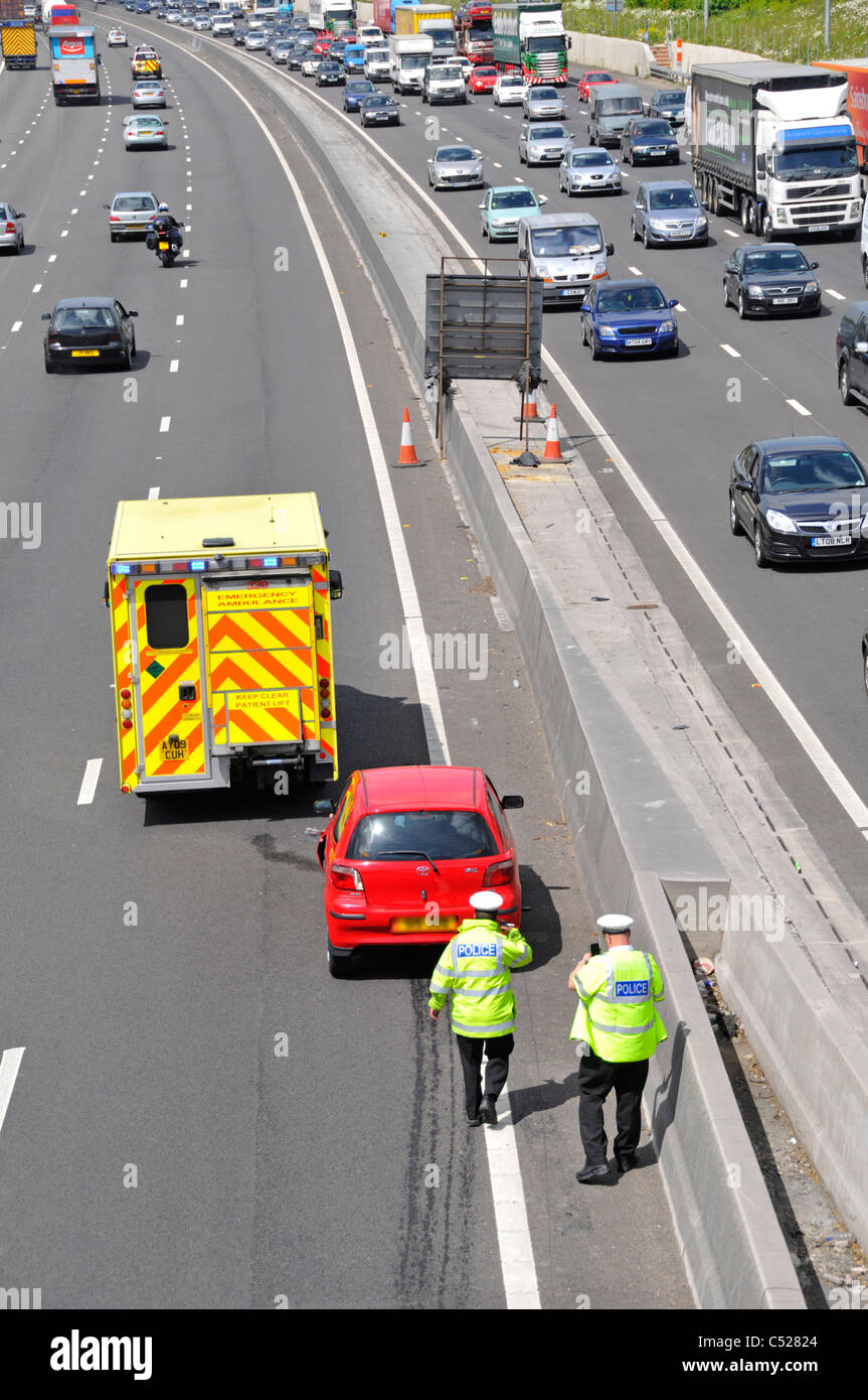 Aerial view traffic police inspecting car involved in road accident includes stationary ambulance (note skid marks) M25 motorway Essex England UK Stock Photo