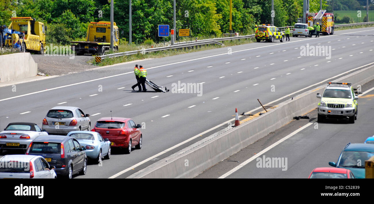 Motorway emergency services attending to two accidents on opposite carriageways, Highways Agency traffic officers clear debris Stock Photo