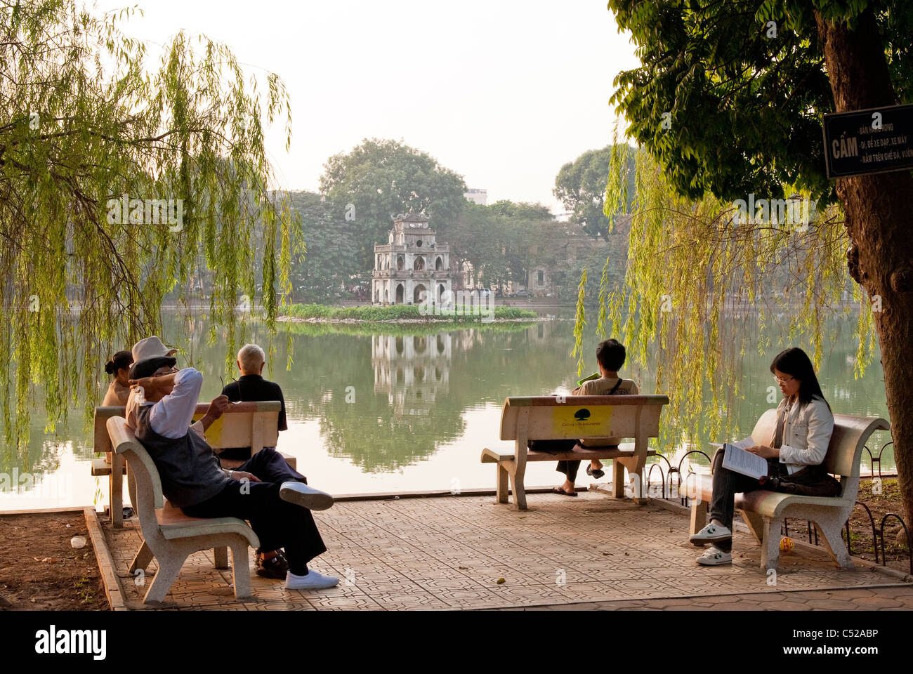 People sitting on lakeside benches, Hoan Kiem Lake, Hanoi, Vietnam Stock Photo