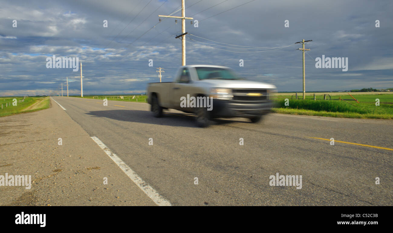 Pick up truck driving down an empty highway in Alberta Canada Stock Photo