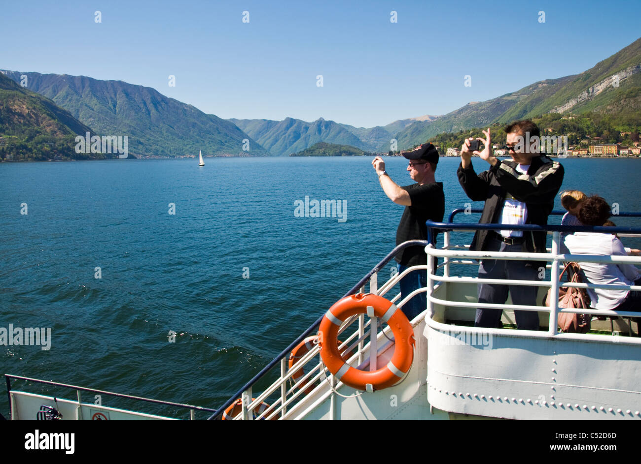 Tourists take digital photographs from a ferry on Lake Como Stock Photo