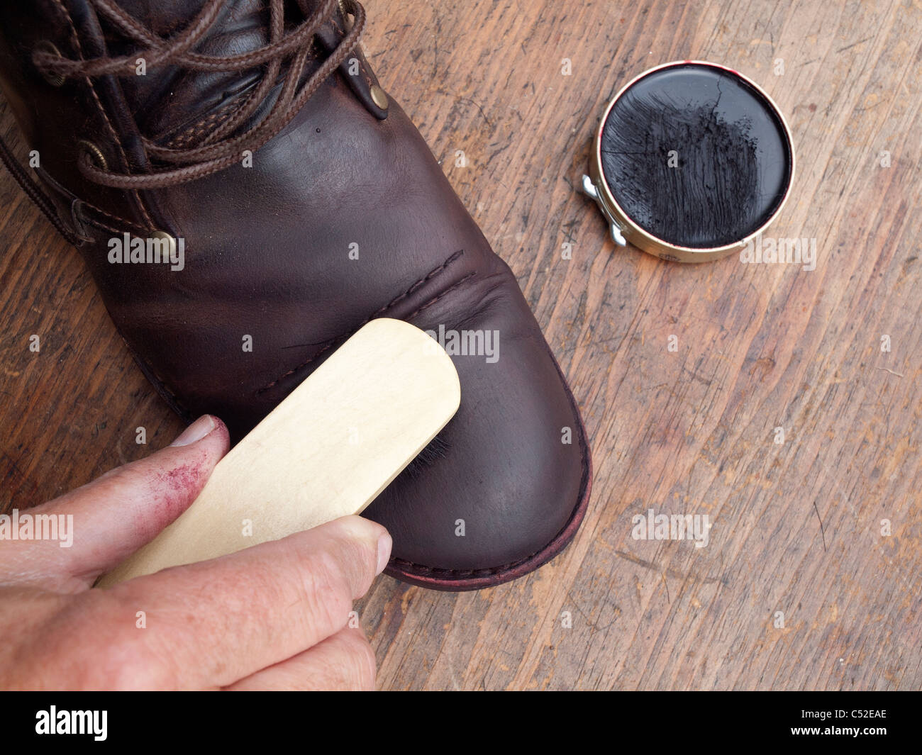 Applying polish to a brown boot using a brush Stock Photo