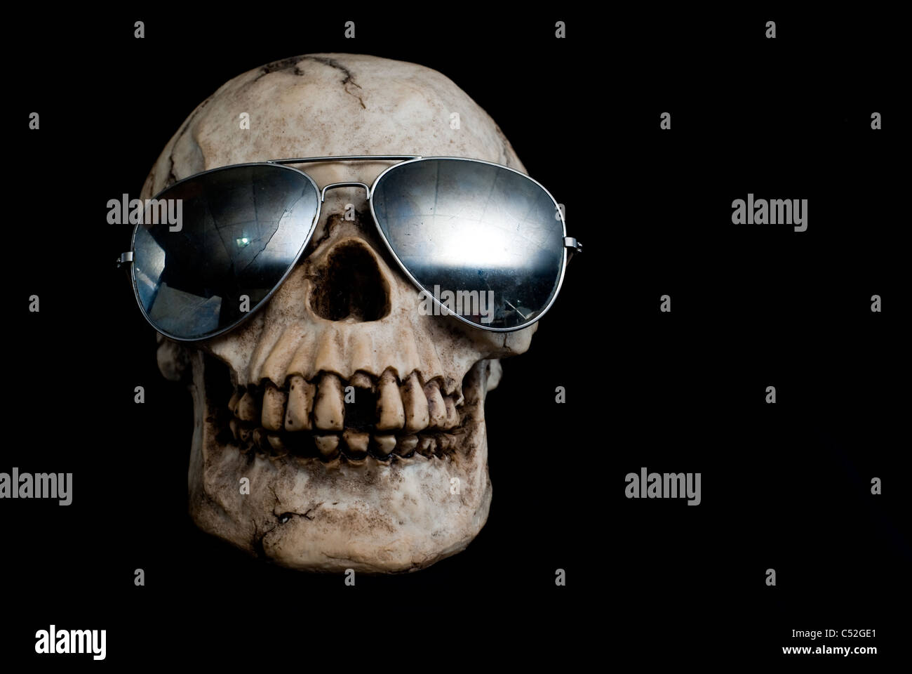 An old, human skull wearing mirrored aviator type sunglasses. Stock Photo