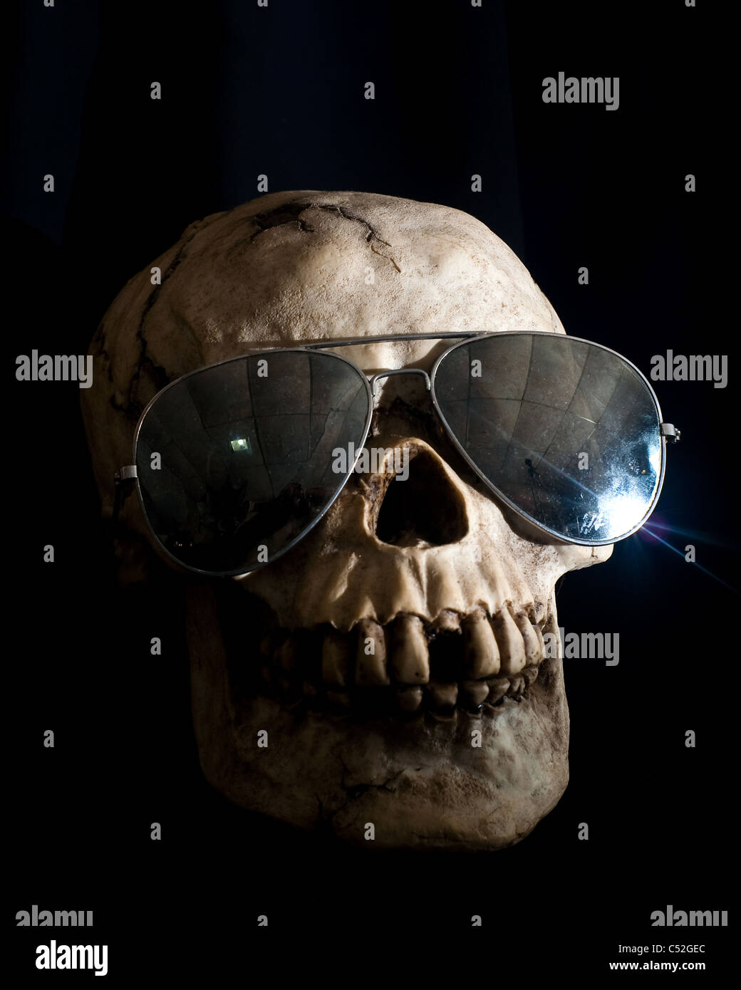 Human skull in shadow wearing mirrored aviator sunglasses Stock Photo