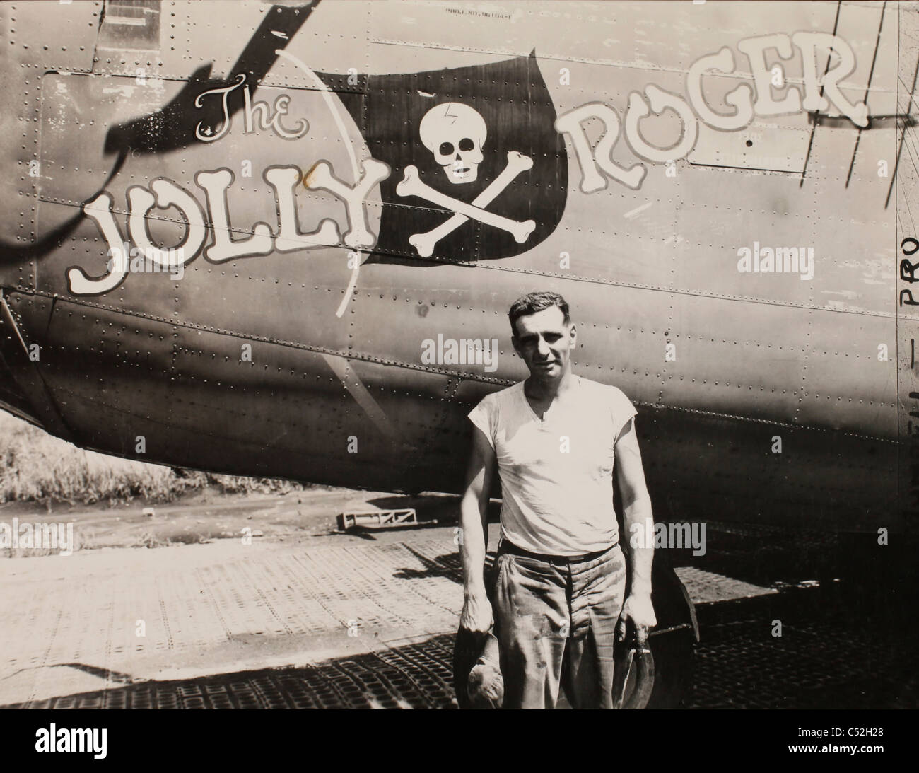 Master Sgt. Robert Porter standing beside a b-24 liberator bomber called 'The Jolly Roger.' It is a veteran of many raids agains Stock Photo