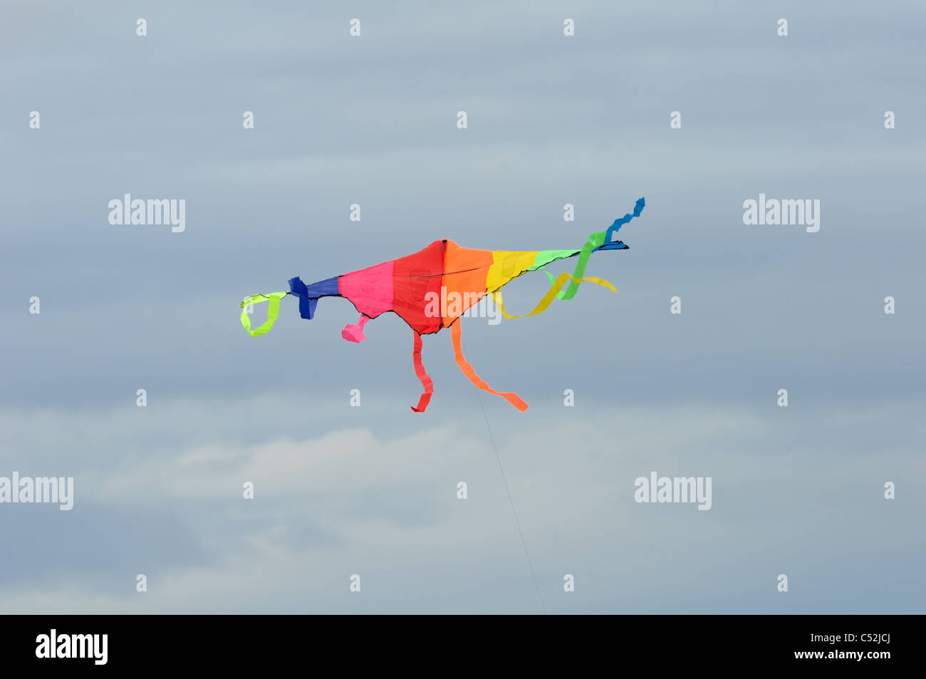 Multi-coloured kite flying high in the sky in the UK Stock Photo