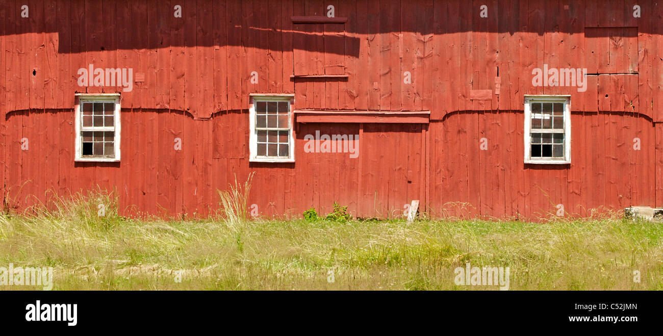 Three White Wood Windows on a Red Weathered Farm Barn of New Jersey Stock Photo