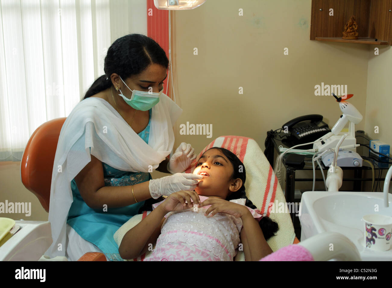 A dentist in India extracting an 8 year old girl's tooth Stock Photo