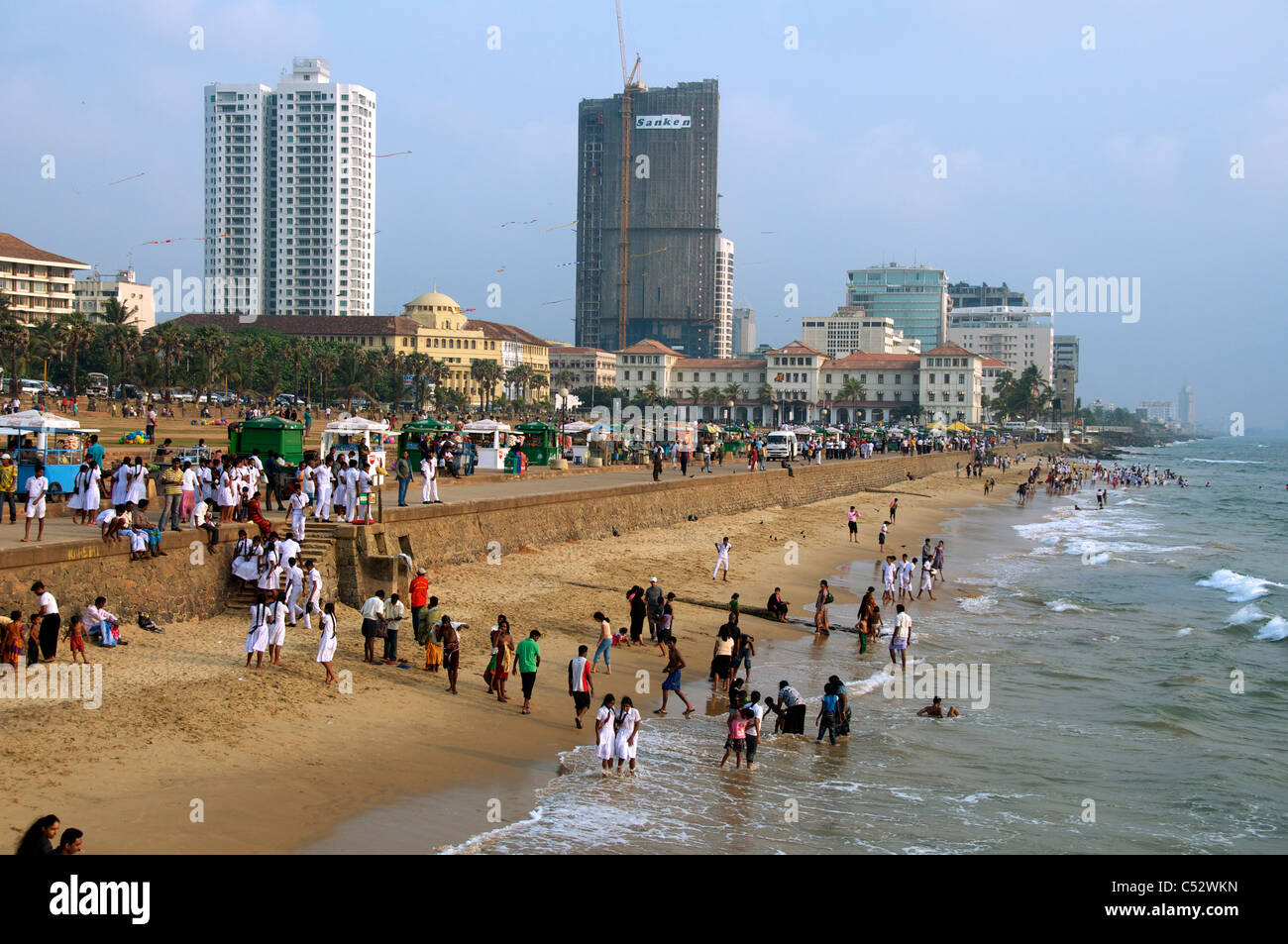 People paddling at waters edge Galle Face Green Beach in late afternoon Colombo Sri Lanka Stock Photo