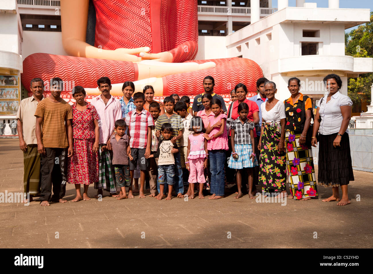 Extended Sinhalese family in front of the Giant sitting Buddha statue in the Weherahena temple of Matara, Sri Lanka, Asia Stock Photo