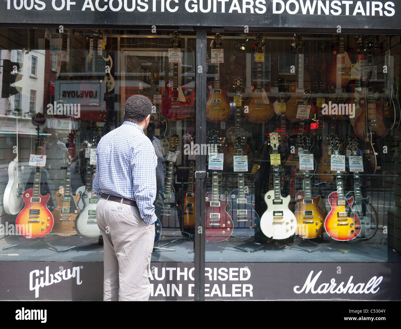 Looking at Gibson guitars in music shop window in Tottenham Court Road, London, England Stock Photo