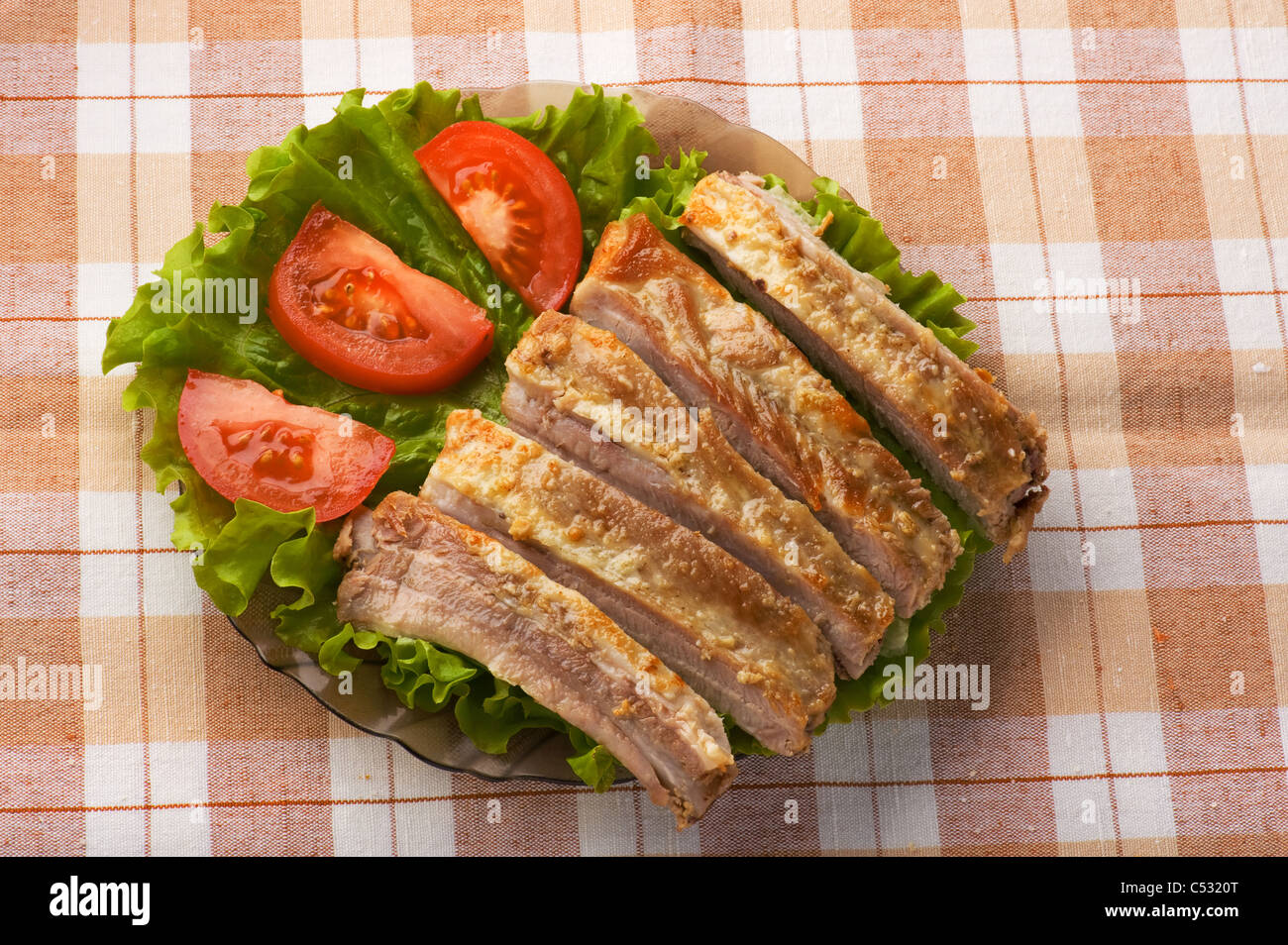 roasted pork ribs in a plate with a cutting tomatoes Stock Photo