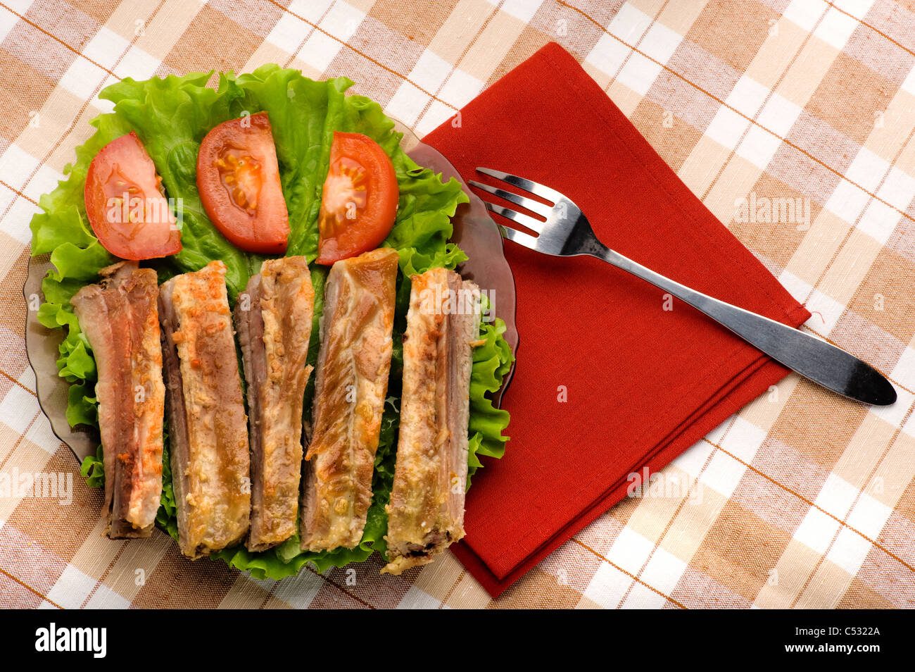 roasted pork ribs in a plate with a cutting tomatoes Stock Photo