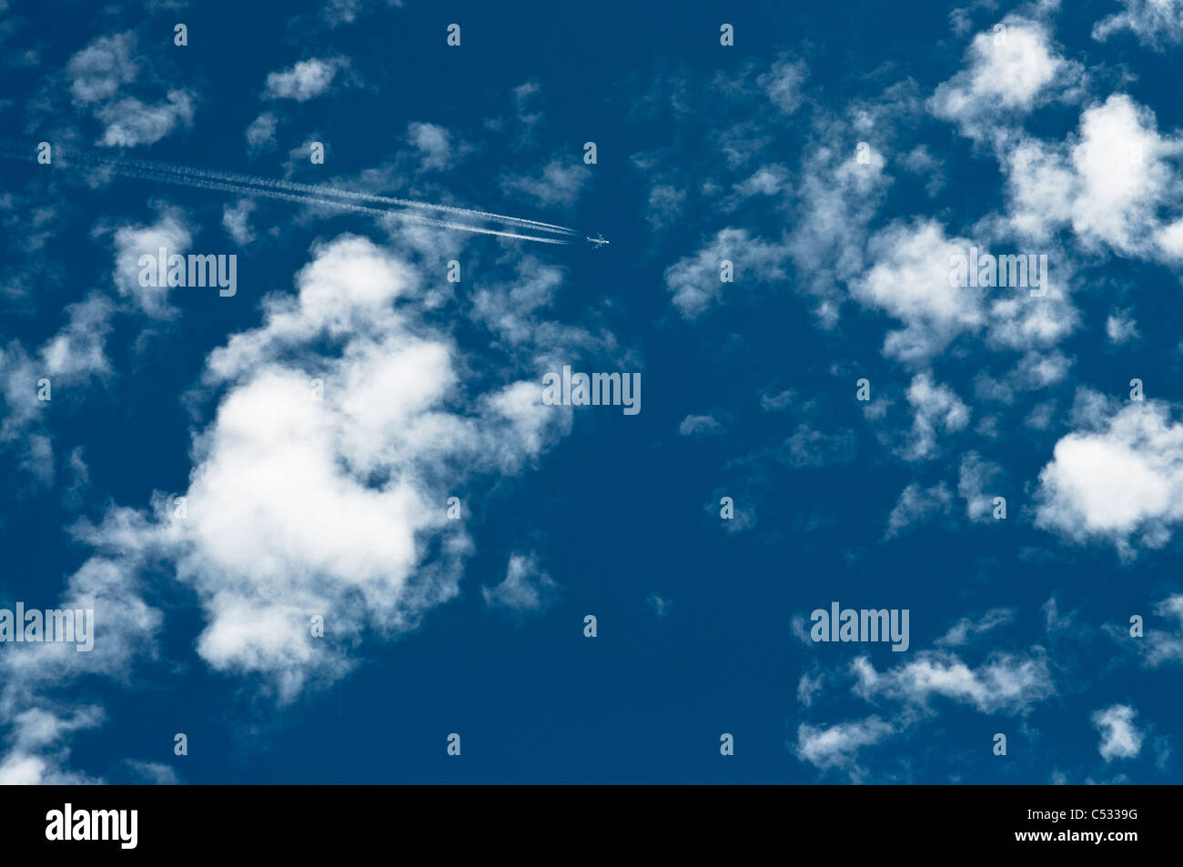Jet Plane Flying in a blue Sky with White Cummulus Cloud Stock Photo ...