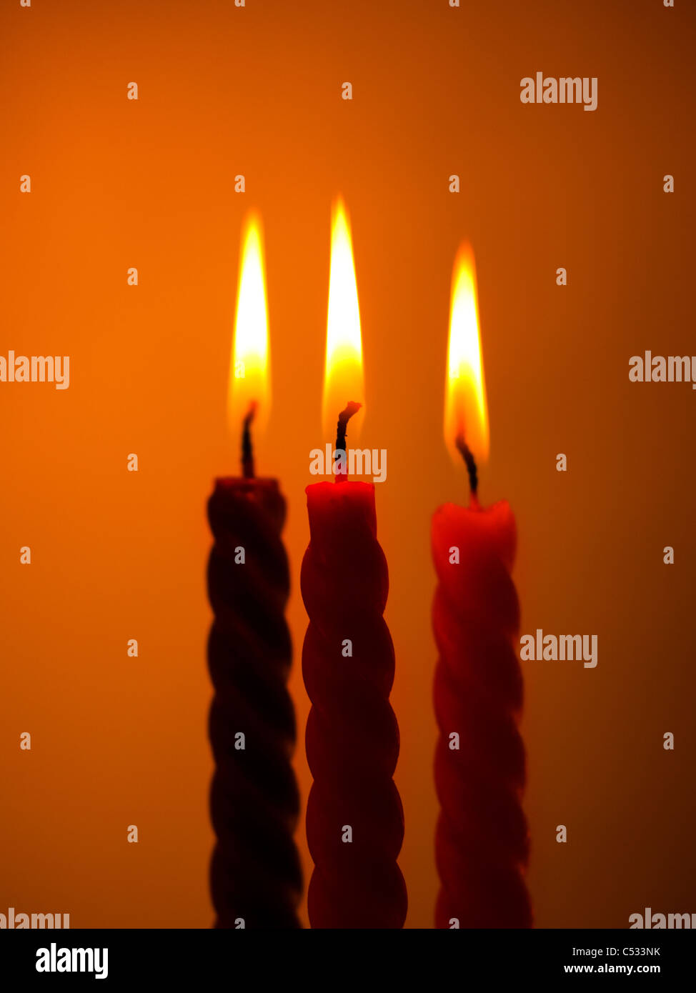 three twisted burning candles over yellow background Stock Photo - Alamy