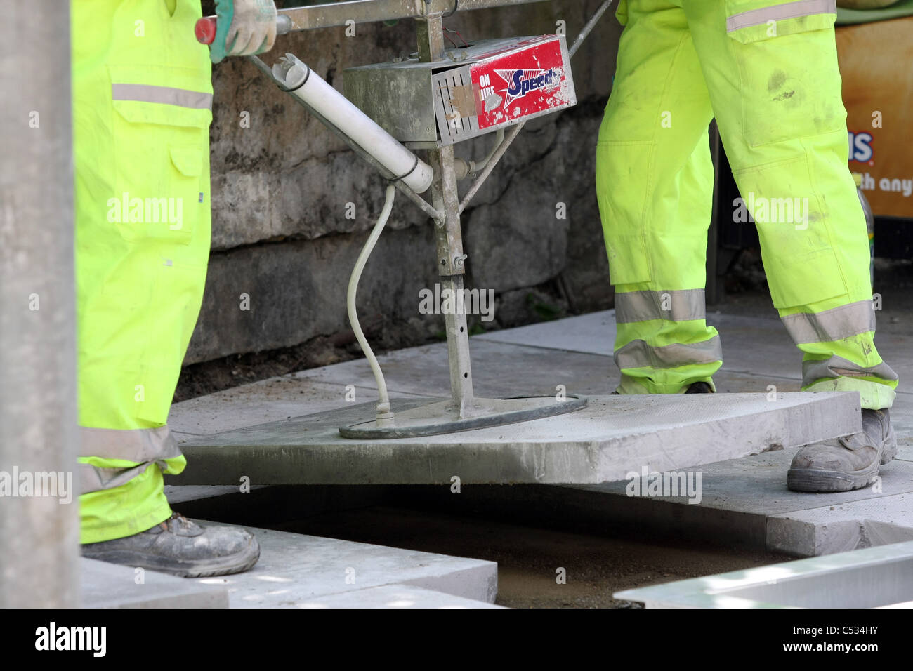 Two  workmen lifting a paving slab using a vacuum lifter Stock Photo