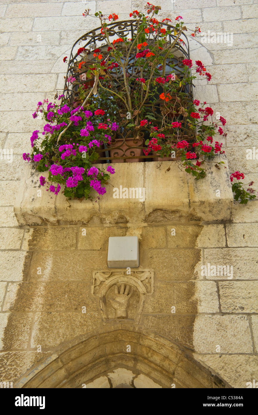 Window covered in flowers above a door with symbolic hand in the Old