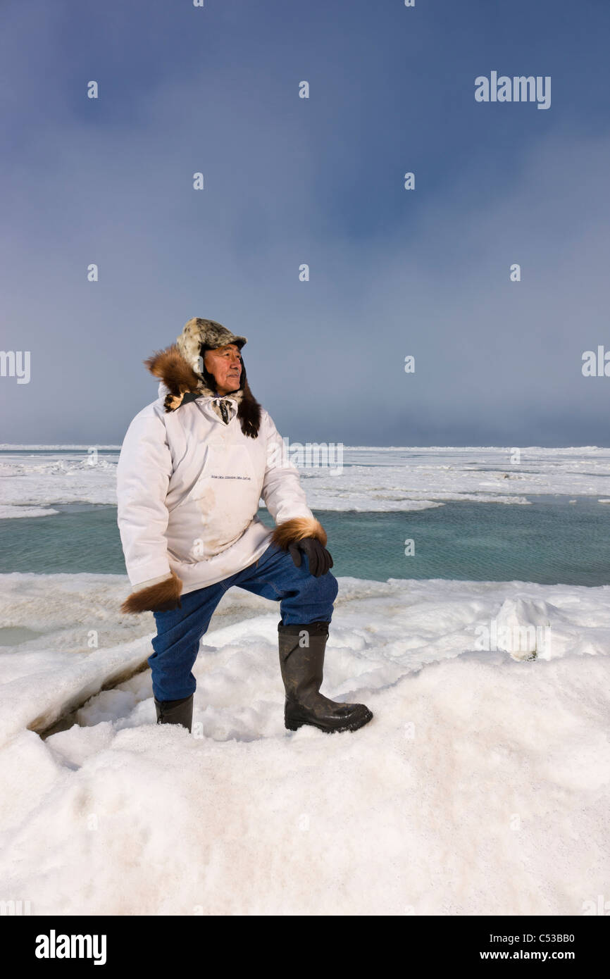 Male Inupiaq Eskimo in traditional park stans on a ice pressure ridges ...