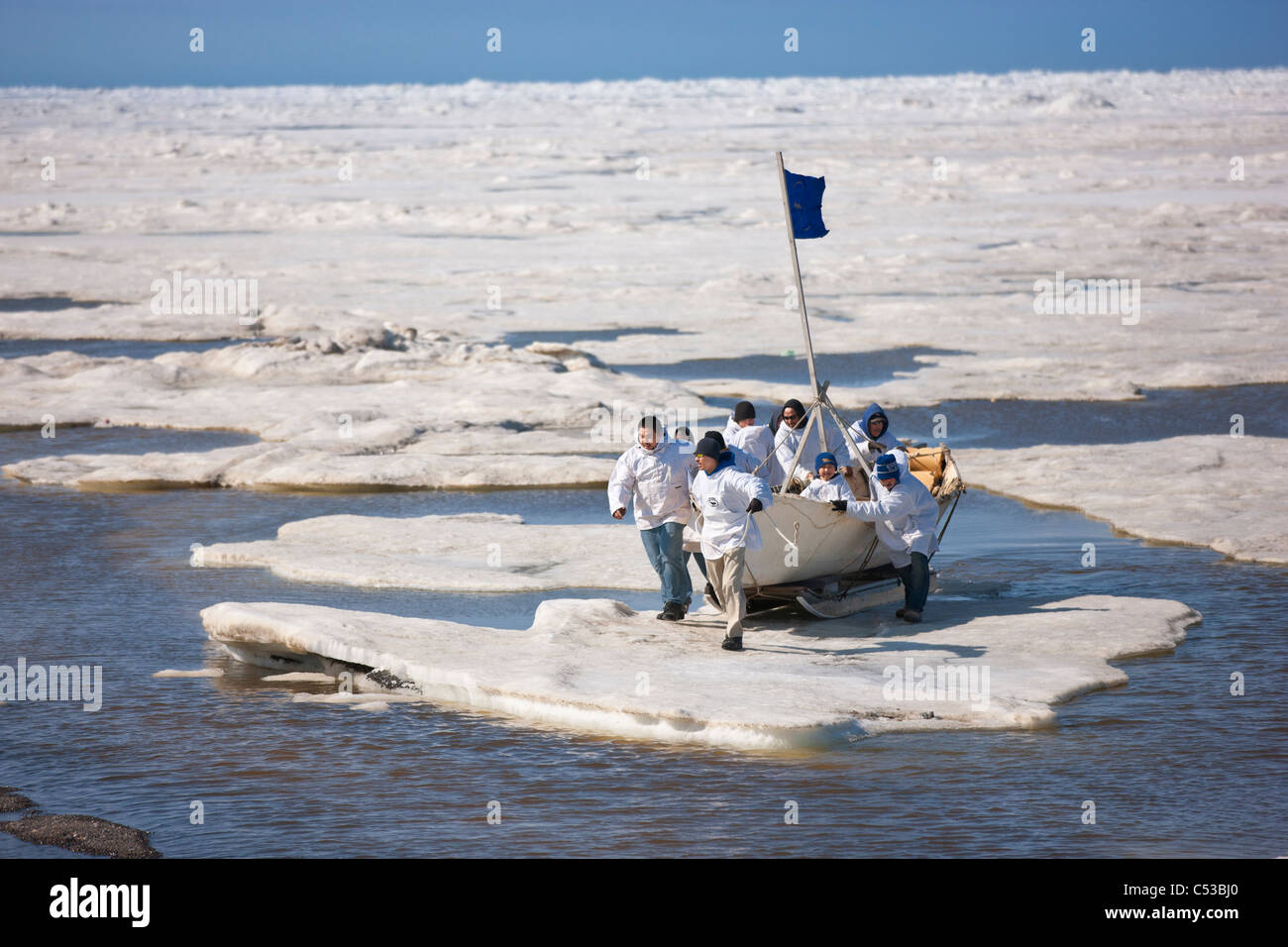 Whaling crew pushes their Umiaq off the Chuchki Sea ice at the end of the spring whaling season in Barrow, Arctic Alaska, Summer Stock Photo