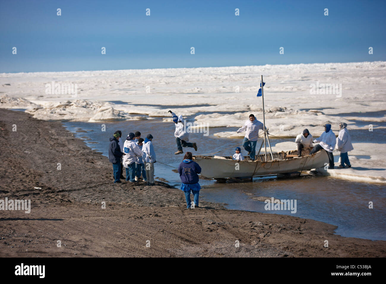 Whaling crew pushes their Umiaq off the Chuchki Sea ice at the end of the spring whaling season in Barrow, Arctic Alaska, Summer Stock Photo