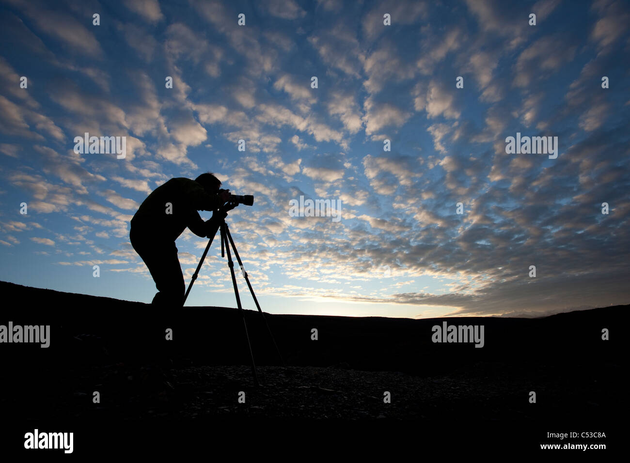 Photographer silhouetted as he photographs on top of Blueberry Hill near Wonder Lake, Denali National Park and Preserve, Alaska Stock Photo