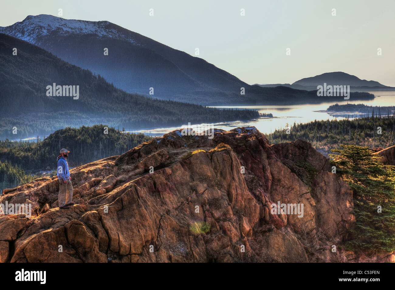 Scenic view of Annette island and surrounding coastal area with male hiker in the foreground, Inside Passage, Southeast Alaska Stock Photo