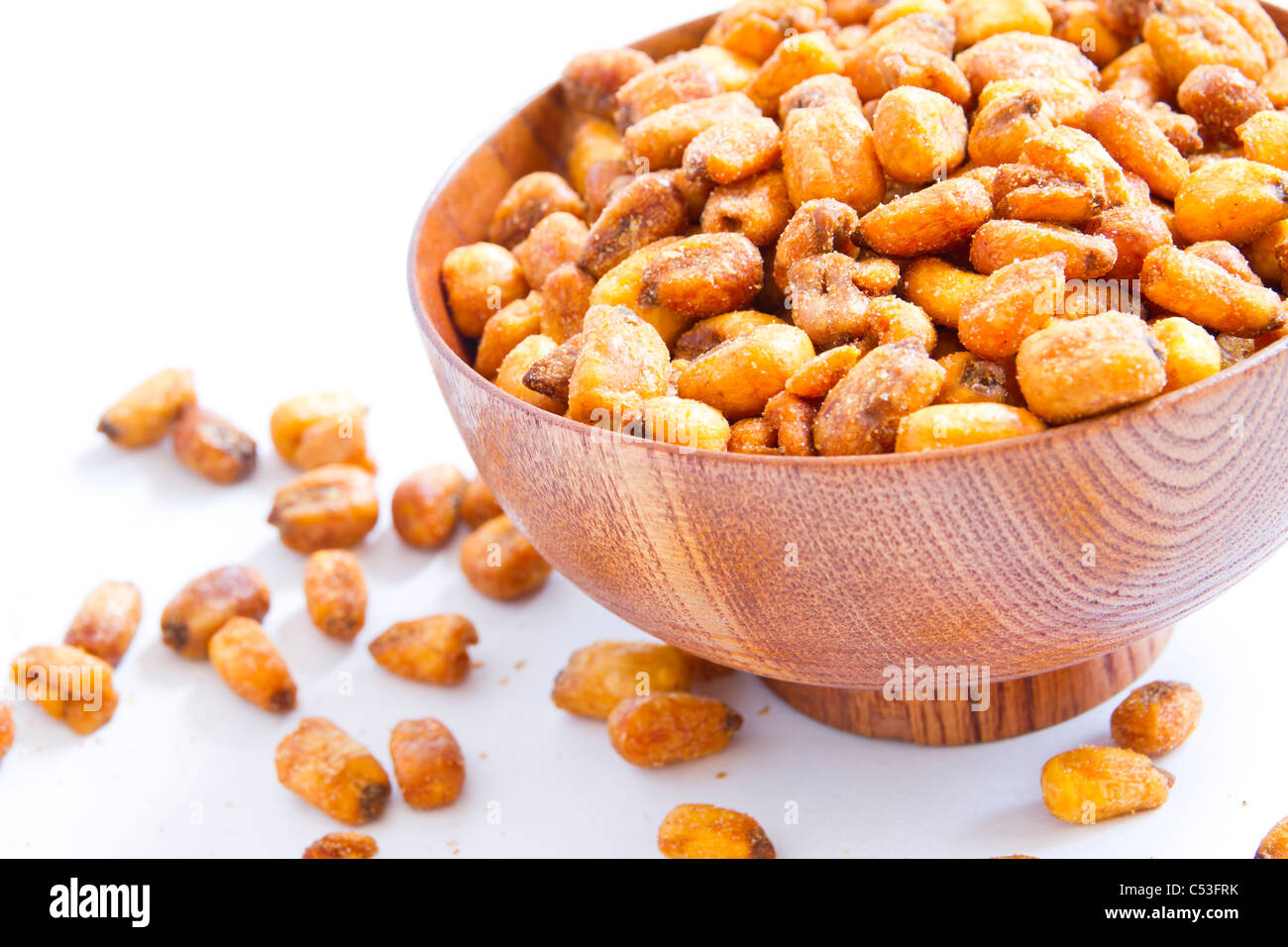 A cherry wood bowl of shelled grains corn fried on a white background. Stock Photo