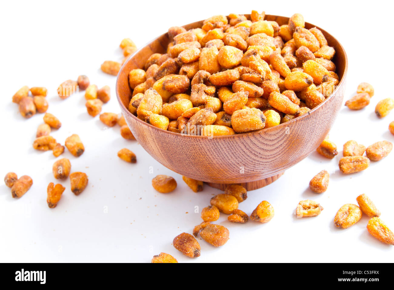 A cherry wood bowl of shelled peanuts on a white background. Stock Photo