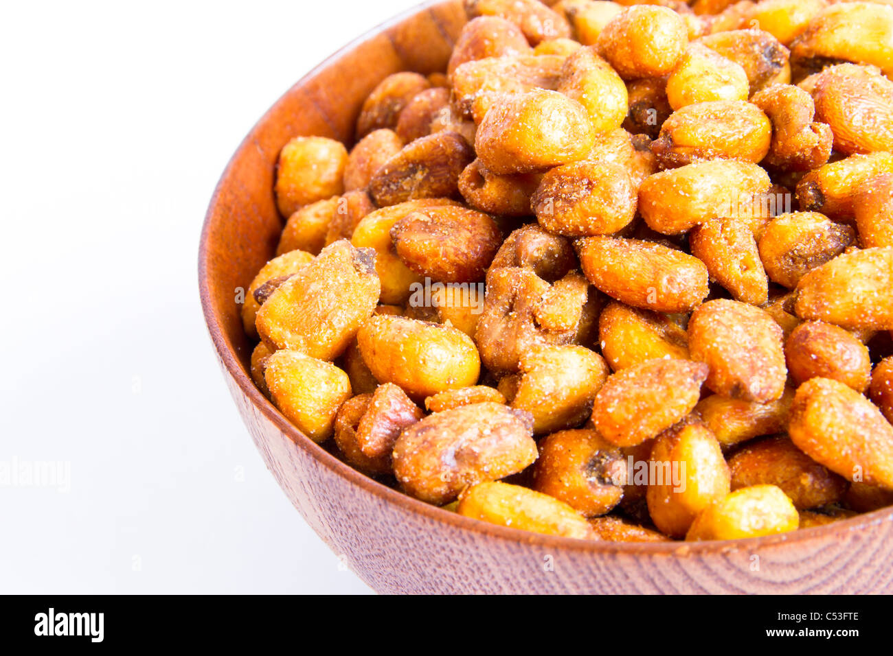 A cherry wood bowl of shelled grains corn fried on a white background. Stock Photo
