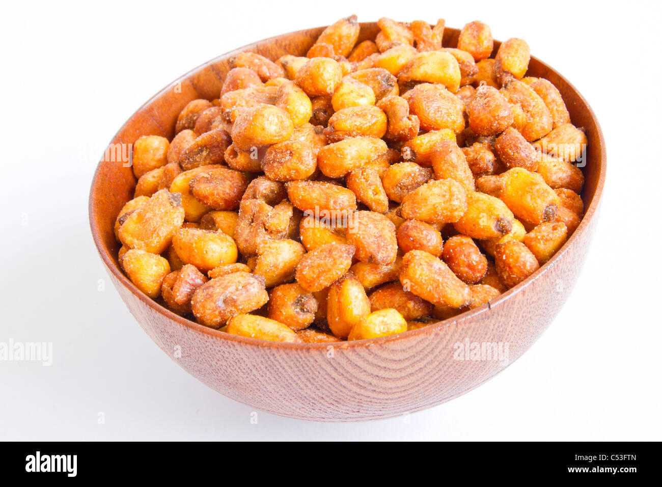 A cherry wood bowl of shelled grains corn fried on a white background. Stock Photo