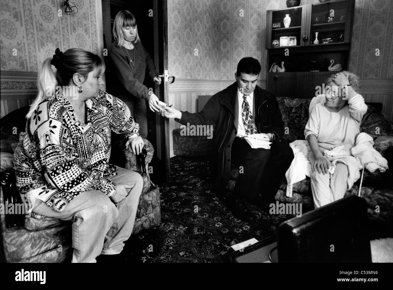 Doctor visiting patient at home and handing a prescription to a member of the family. Liverpool. UK. 1999 Stock Photo