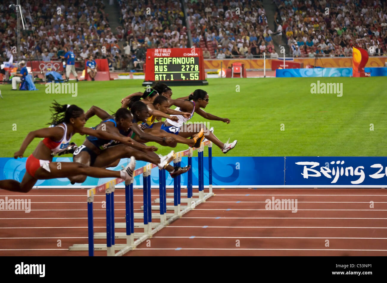 Female athletes clear the hurdles during the women's 110 meter hurdles
