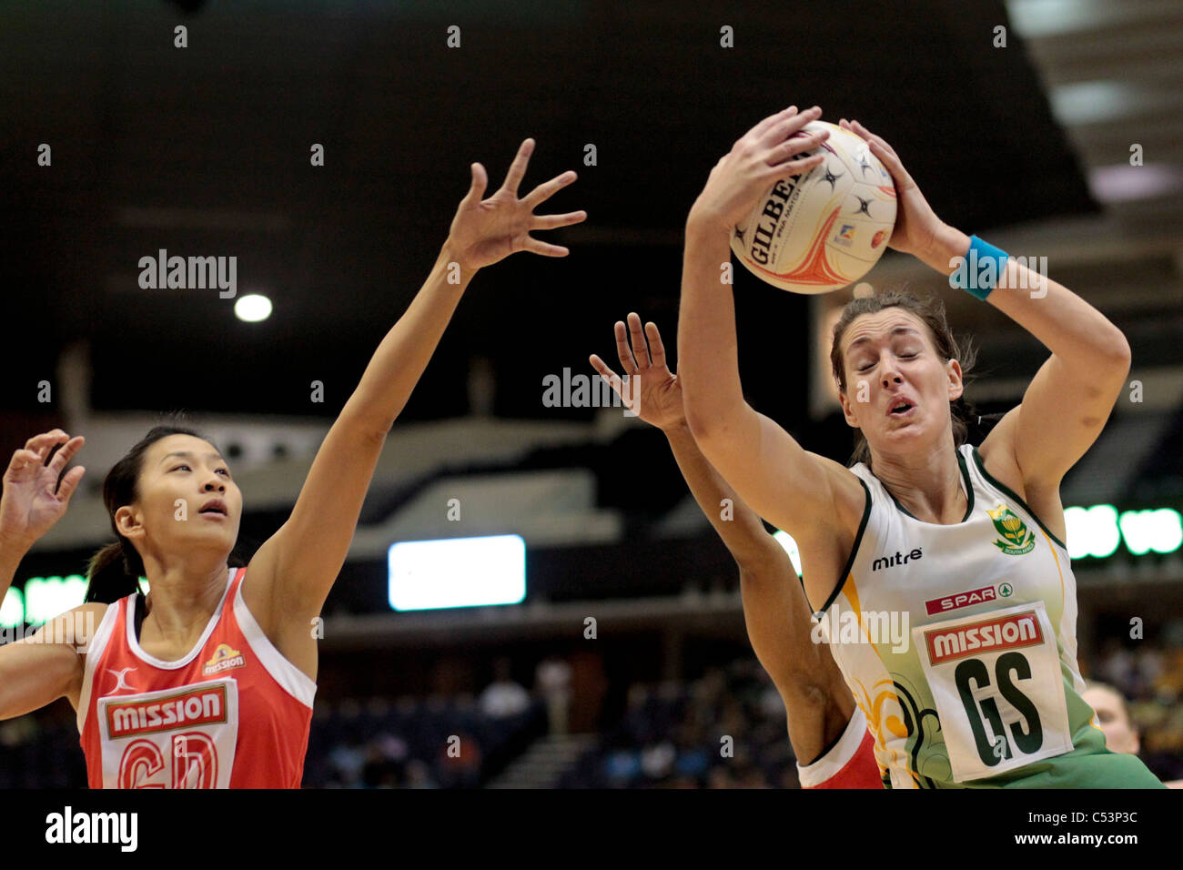 05.07.2011 Claudia Basson of South Africa(right) manages to get her hand to the ball as Jean Ng looks on during the Pool C match between Singapore and South Africa, Mission Foods World Netball Championships 2011 from the Singapore Indoor Stadium in Singapore. Stock Photo